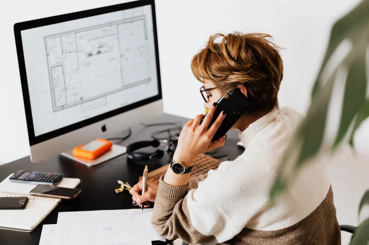 Real Estate Wholesaler reviewing floor plans and taking notes while on a phone call.